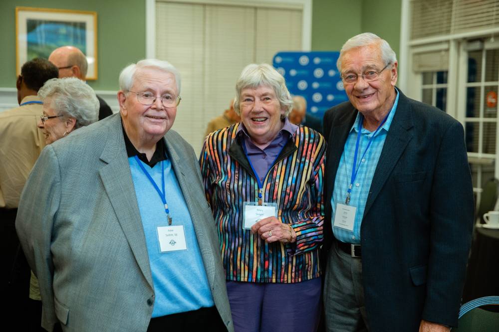 Three alumni pose for a photo together at the Reunion Dinner.